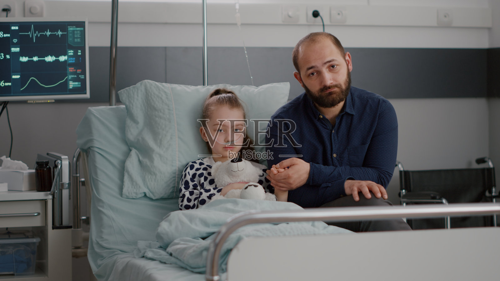 忧心忡忡的父亲握着住院生病的女儿的手看着镜头照片摄影图片