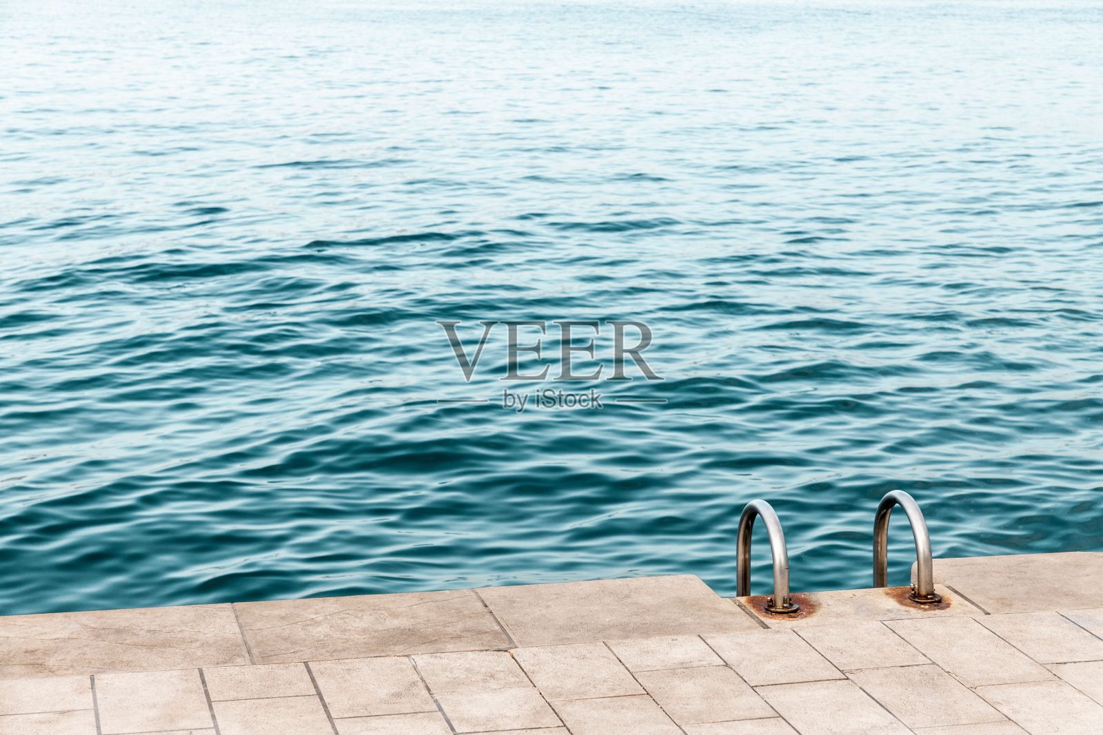 银色的金属楼梯向下延伸到热带海洋明亮的蓝色水域照片摄影图片