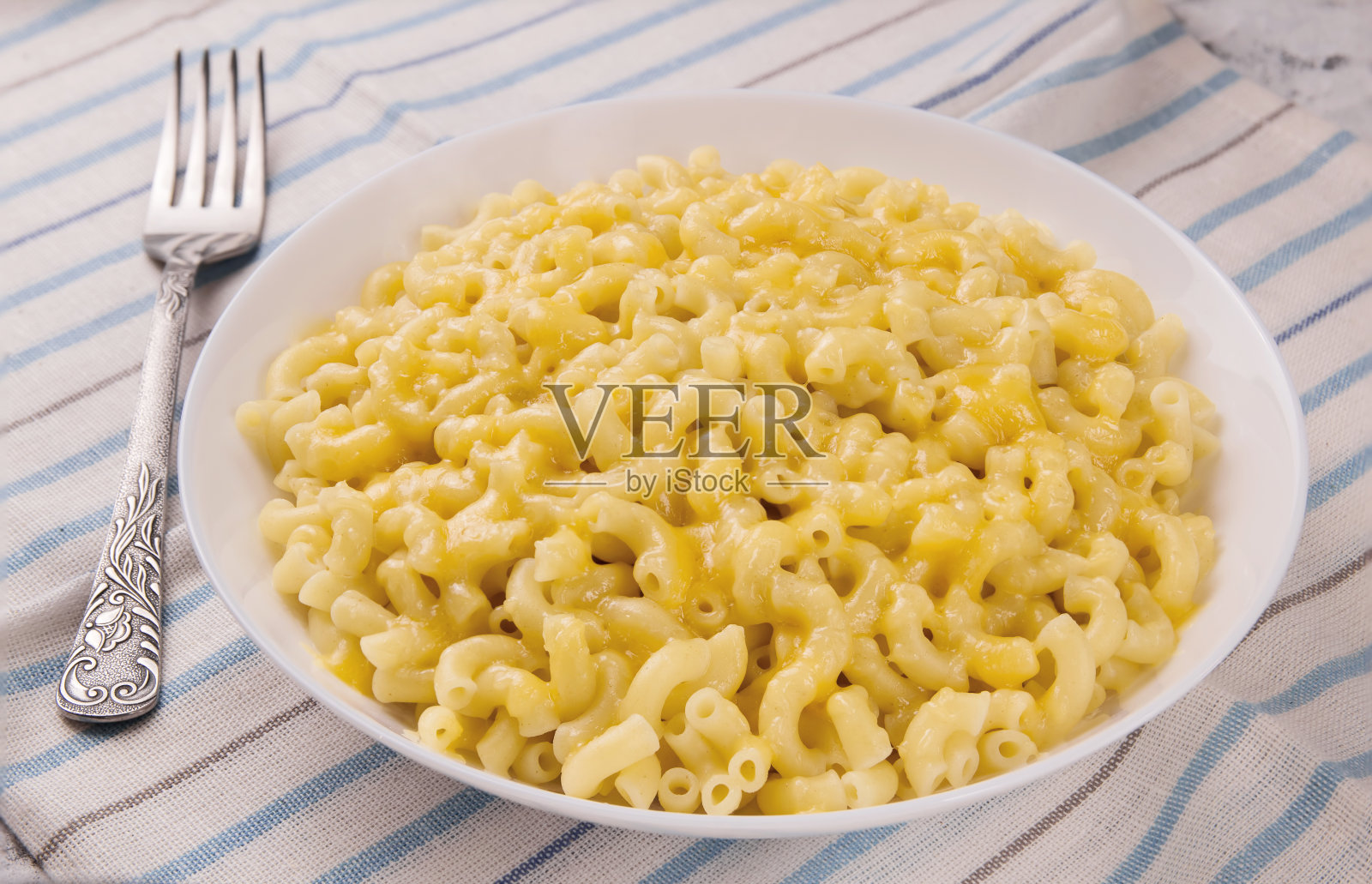 灰色背景上的白色盘子里放着通心粉和奶酪照片摄影图片