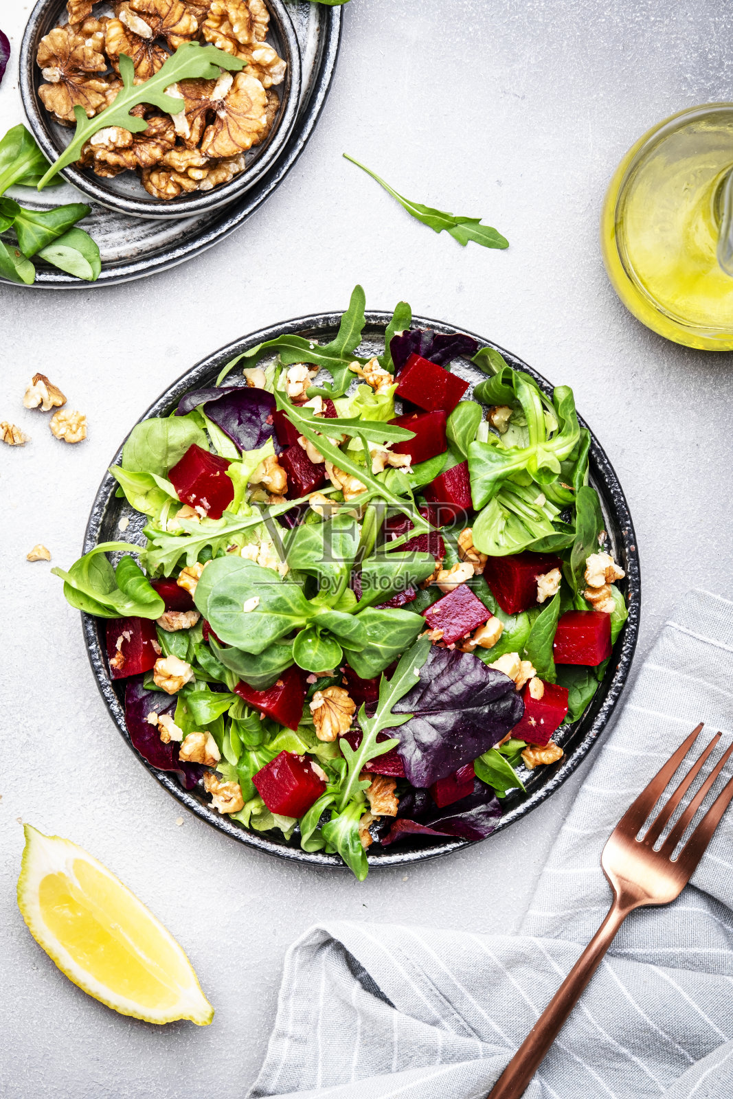 甜菜沙拉与芝麻菜，生菜，甜菜和核桃和柠檬酱，灰色的厨房桌子，复制空间。新鲜实用的素食，健康饮食照片摄影图片