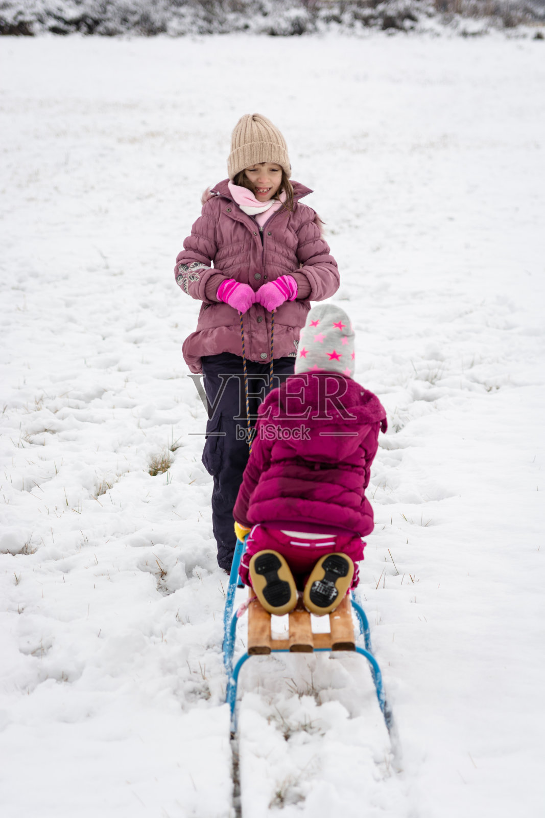 冬日里，孩子们在户外玩白色的雪橇照片摄影图片