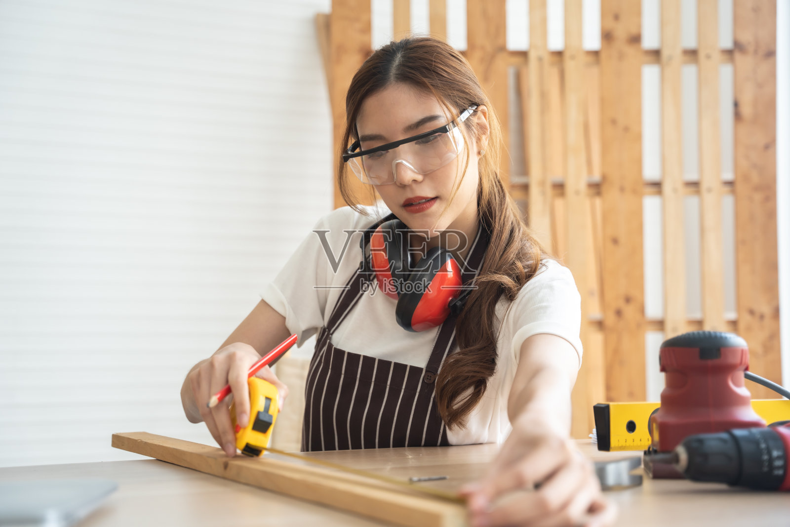 快乐的女木匠在车间工作。照片摄影图片