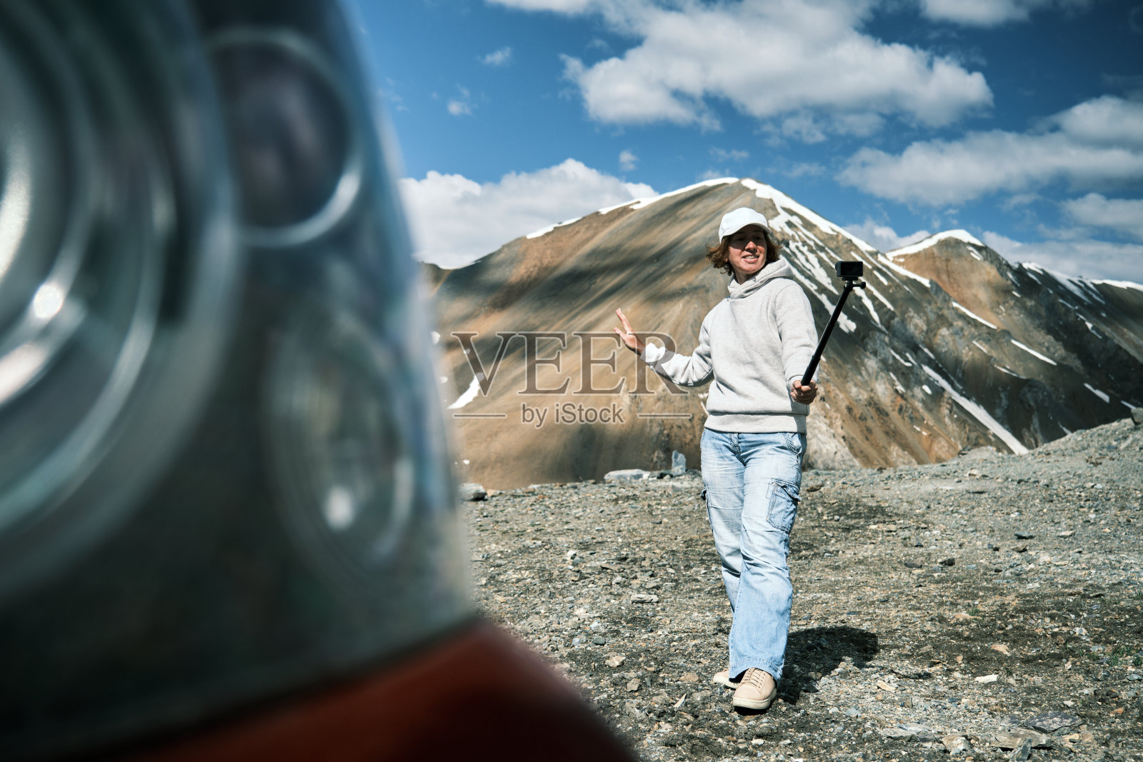 一位兴高采烈的女游客站在车旁边，正在拍摄她在天山自驾游的视频照片摄影图片