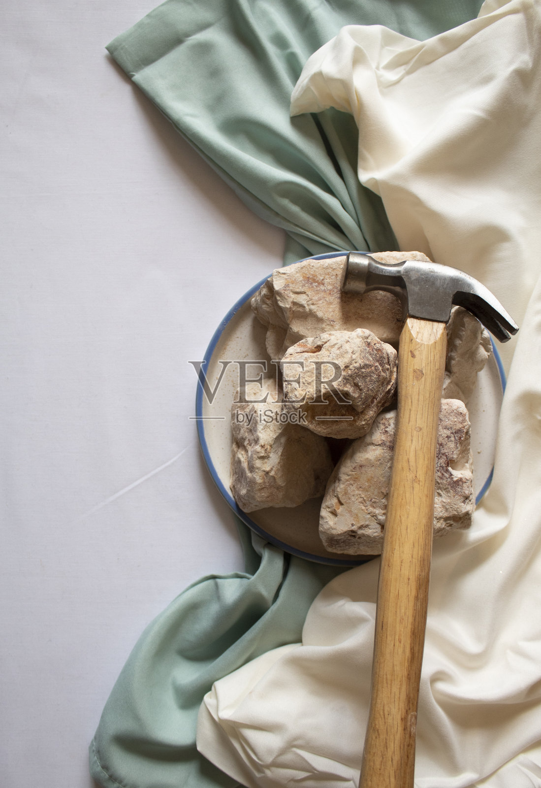 可食用的白色粘土石头在圆形盘子上用锤子平铺照片摄影图片