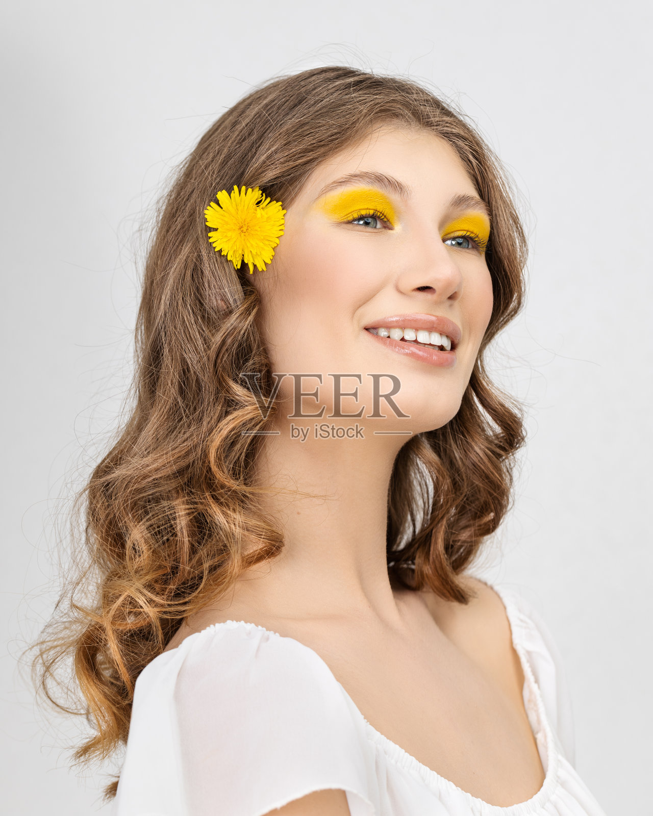 穿着白色裙子的漂亮女人拿着蒲公英花照片摄影图片