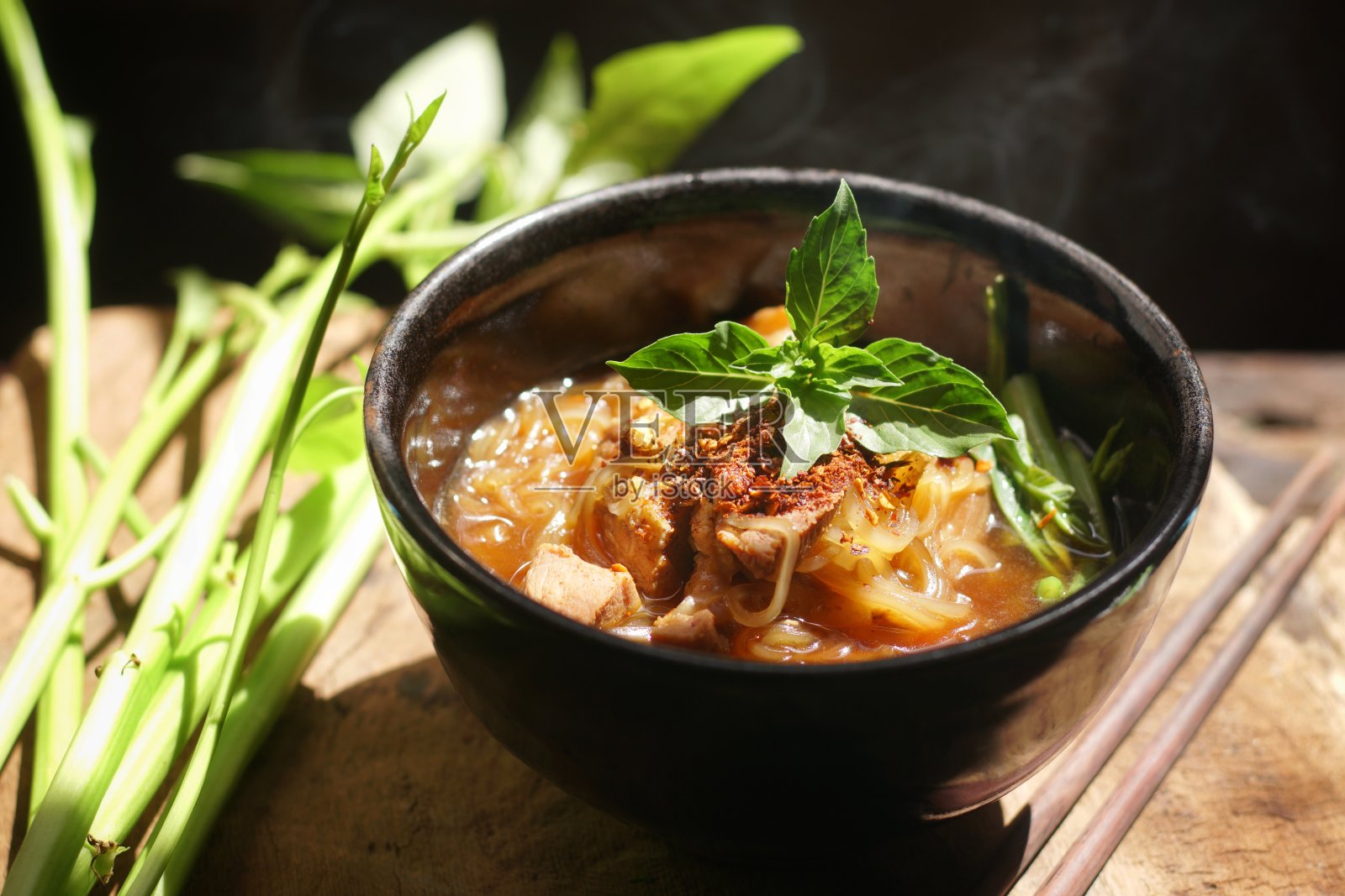 厨师在黑背景下用蒸汽和烟在煎锅里煮面，亚洲饮食风格，热食和快餐的概念。照片摄影图片