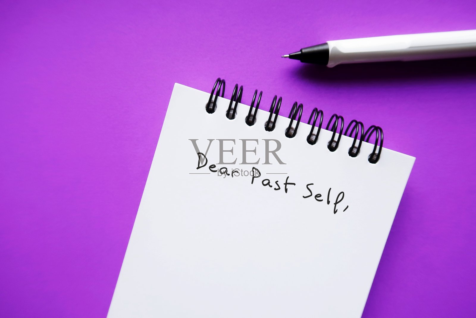 笔记本和笔在紫色的背景上手写文字亲爱的过去的自己，自我反思的概念——给过去的自己写一封信，告诉他们过去和现在发生的事情照片摄影图片
