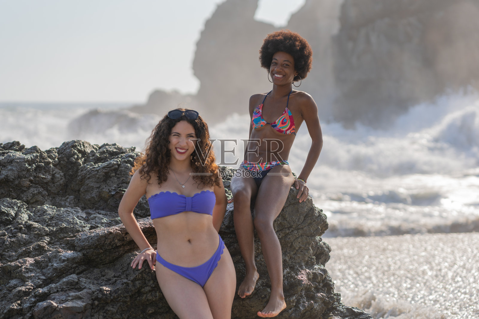 女人们在沙滩上的岩石上摆姿势照片摄影图片