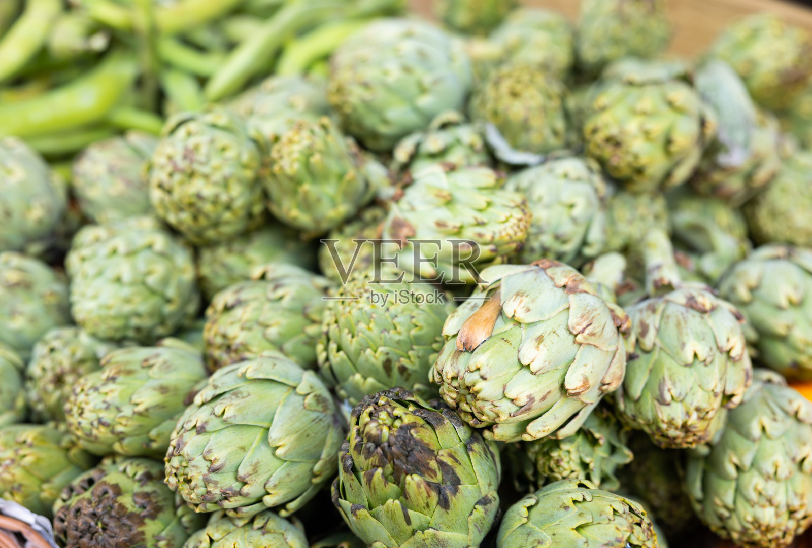 农贸市场摊位上的一堆生的绿色洋蓟照片摄影图片