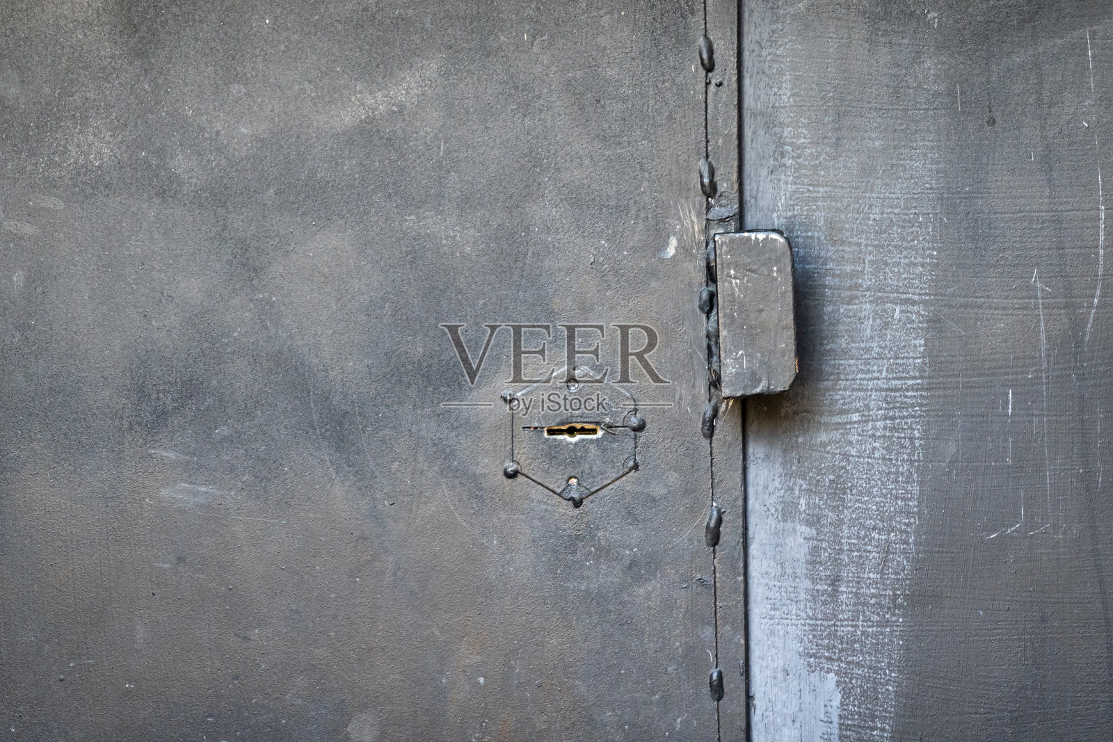 一扇黑色粗糙铁门的碎片。有一个钥匙孔和一个简单的金属把手。背景。纹理。照片摄影图片