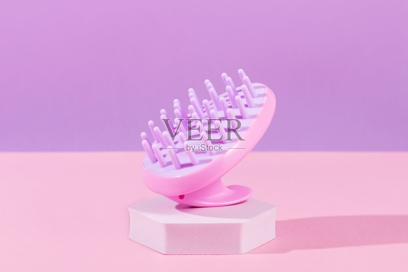 粉红色的头皮按摩和清洁洗发水刷在紫色的背景，特写照片摄影图片