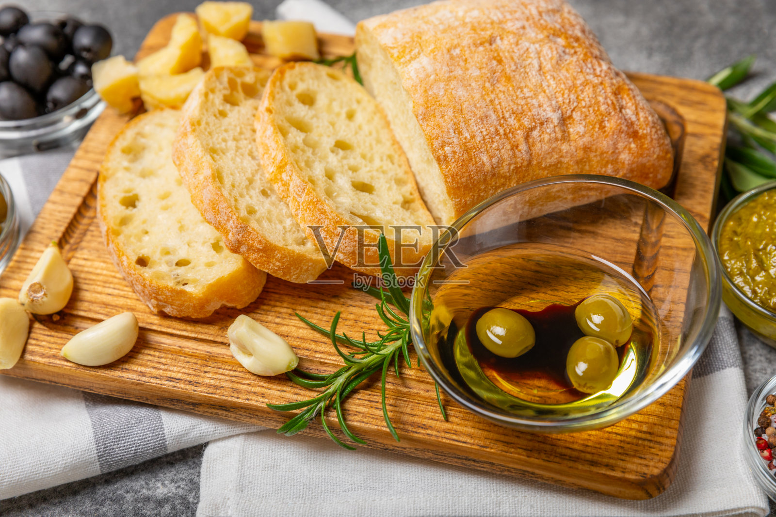 ciabatta，一碗橄榄油，配上橄榄、香草、香料、大蒜、香蒜酱、帕尔马干酪和ciabatta面包。健康食品理念，美味。地中海厨房。副本的空间。照片摄影图片