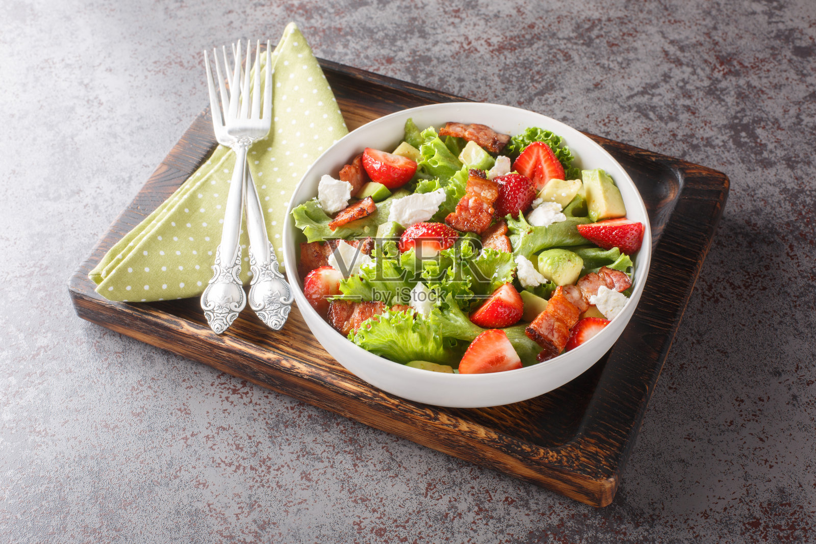 自制新鲜的草莓沙拉，牛油果，培根，生菜，羊乳酪特写在一个碗里。水平照片摄影图片
