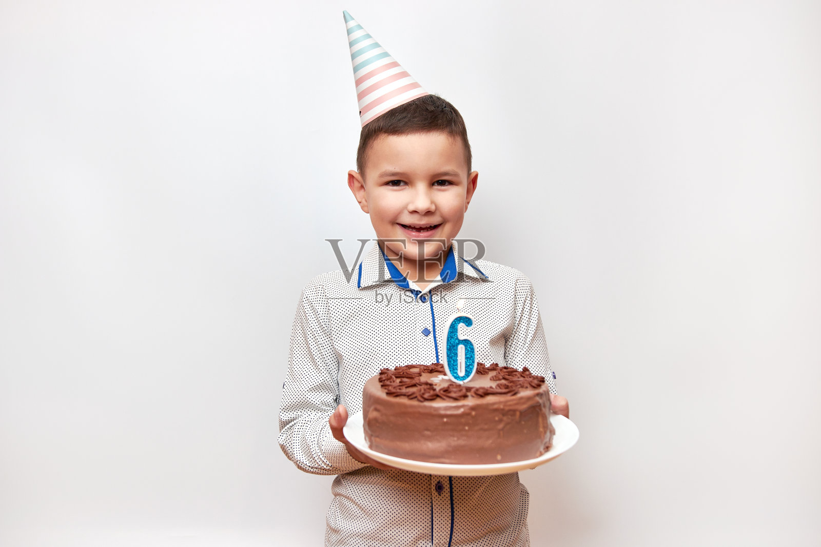 快乐的男孩拿着一个生日蛋糕，上面插着数字6形状的蜡烛。生日庆祝概念。照片摄影图片