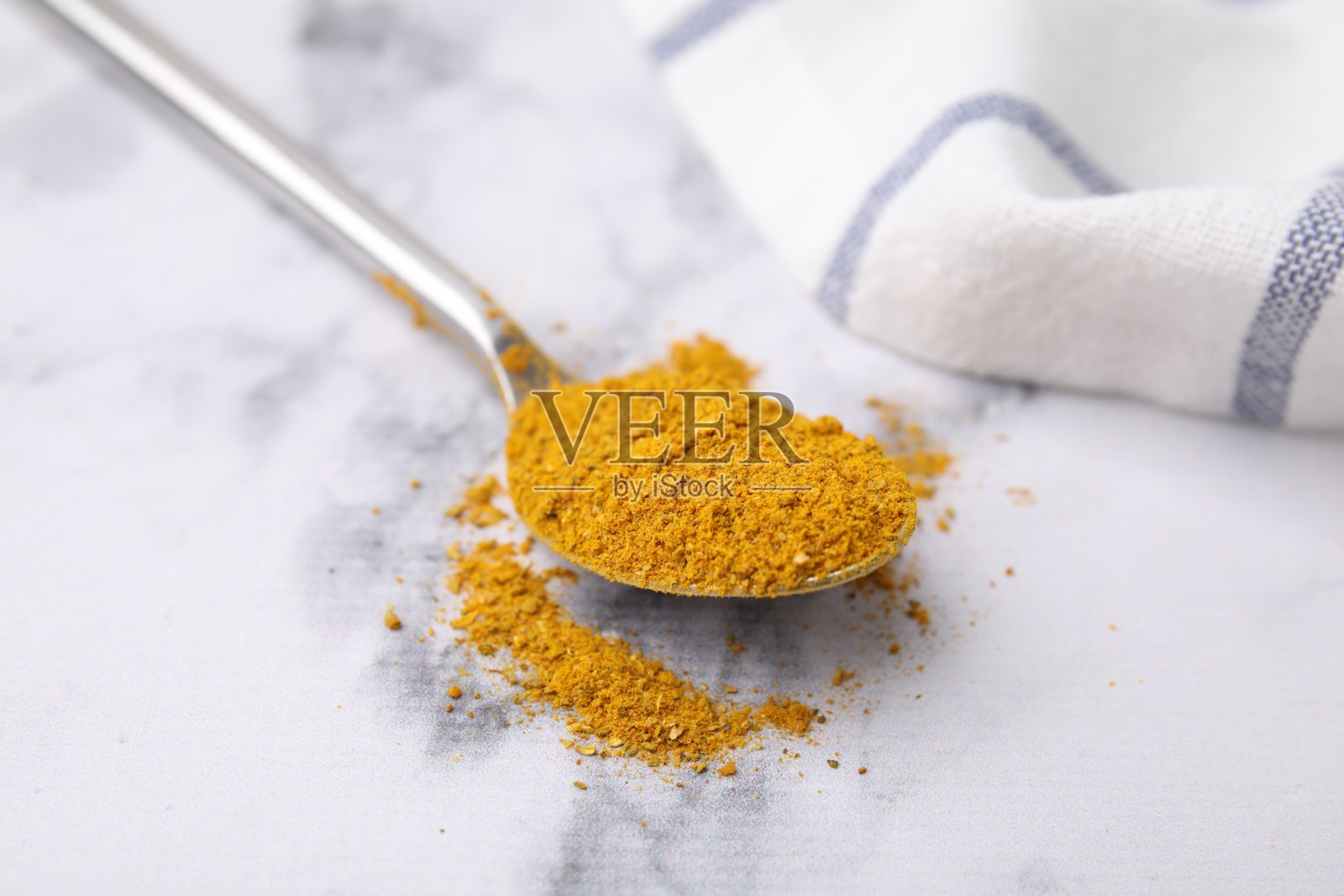 白色大理石桌子上放着咖喱粉的勺子，特写照片摄影图片
