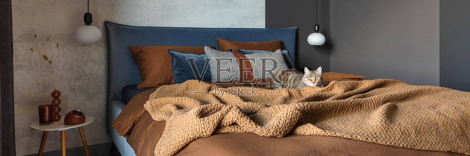 现代卧室室内的时尚构图。床，创意灯和优雅的个人配件。混凝土墙。布朗sheeets。极简的男性概念。模板。照片摄影图片