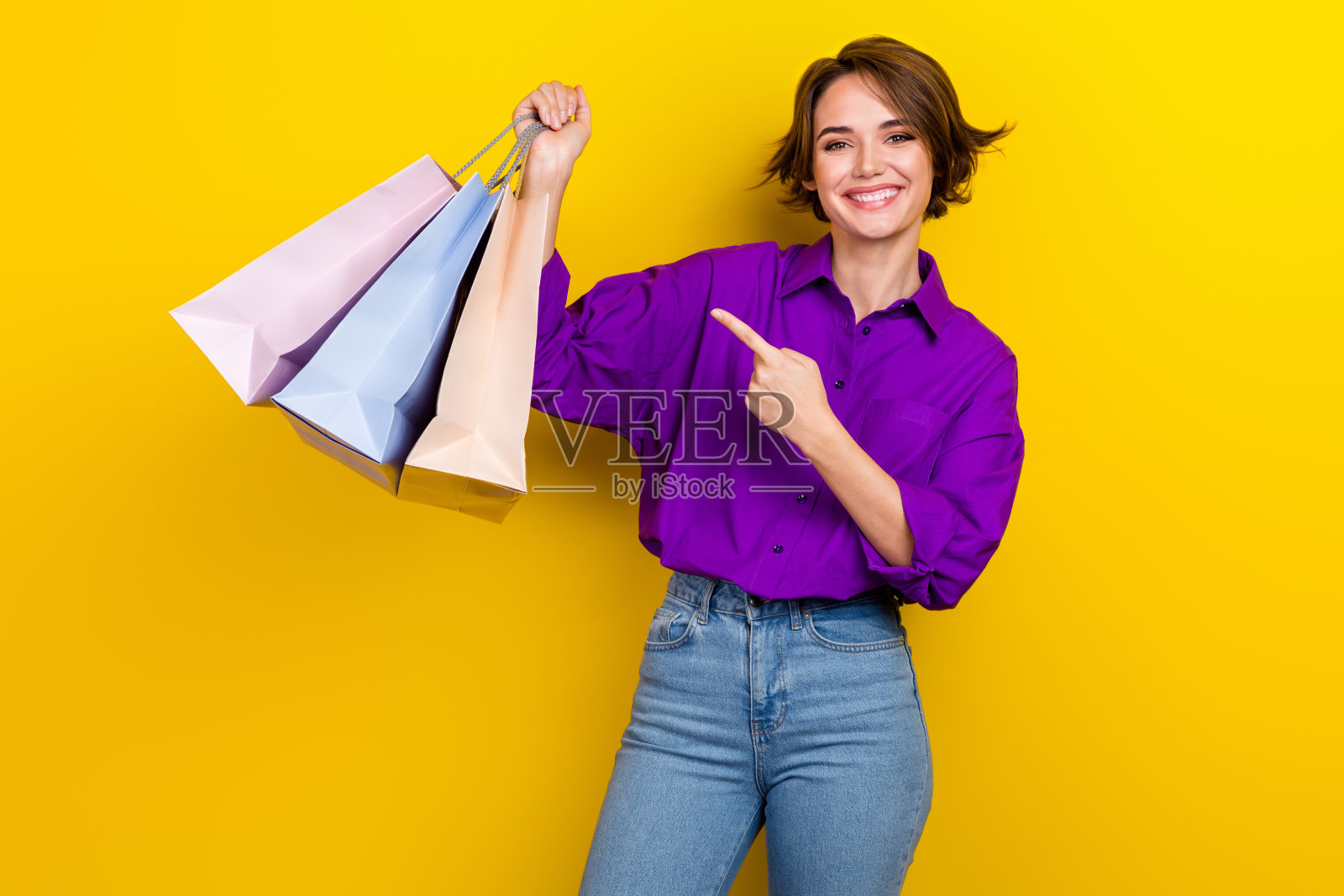 照片肖像可爱的年轻女士点购物袋穿着时尚的紫色智能休闲服装孤立在黄色的背景照片摄影图片