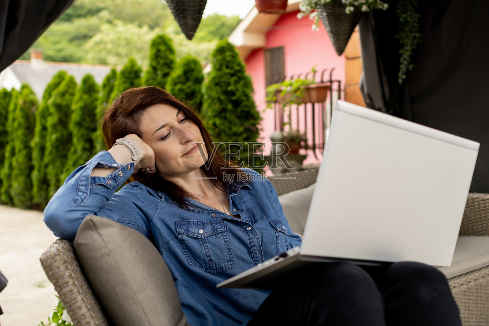 女人在后院放松时使用笔记本电脑。她有个在线会议。网络聊天，连接，在线交流，商务，在家办公，远程学习，学习，科技理念照片摄影图片