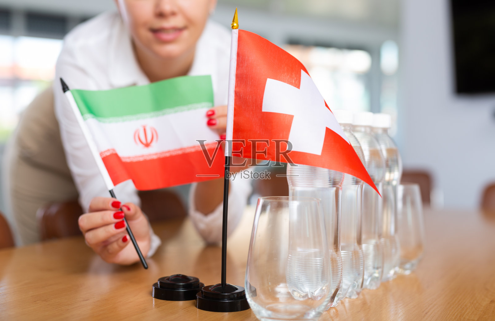 年轻女子把伊朗和瑞士的国旗放在办公室的桌子上照片摄影图片