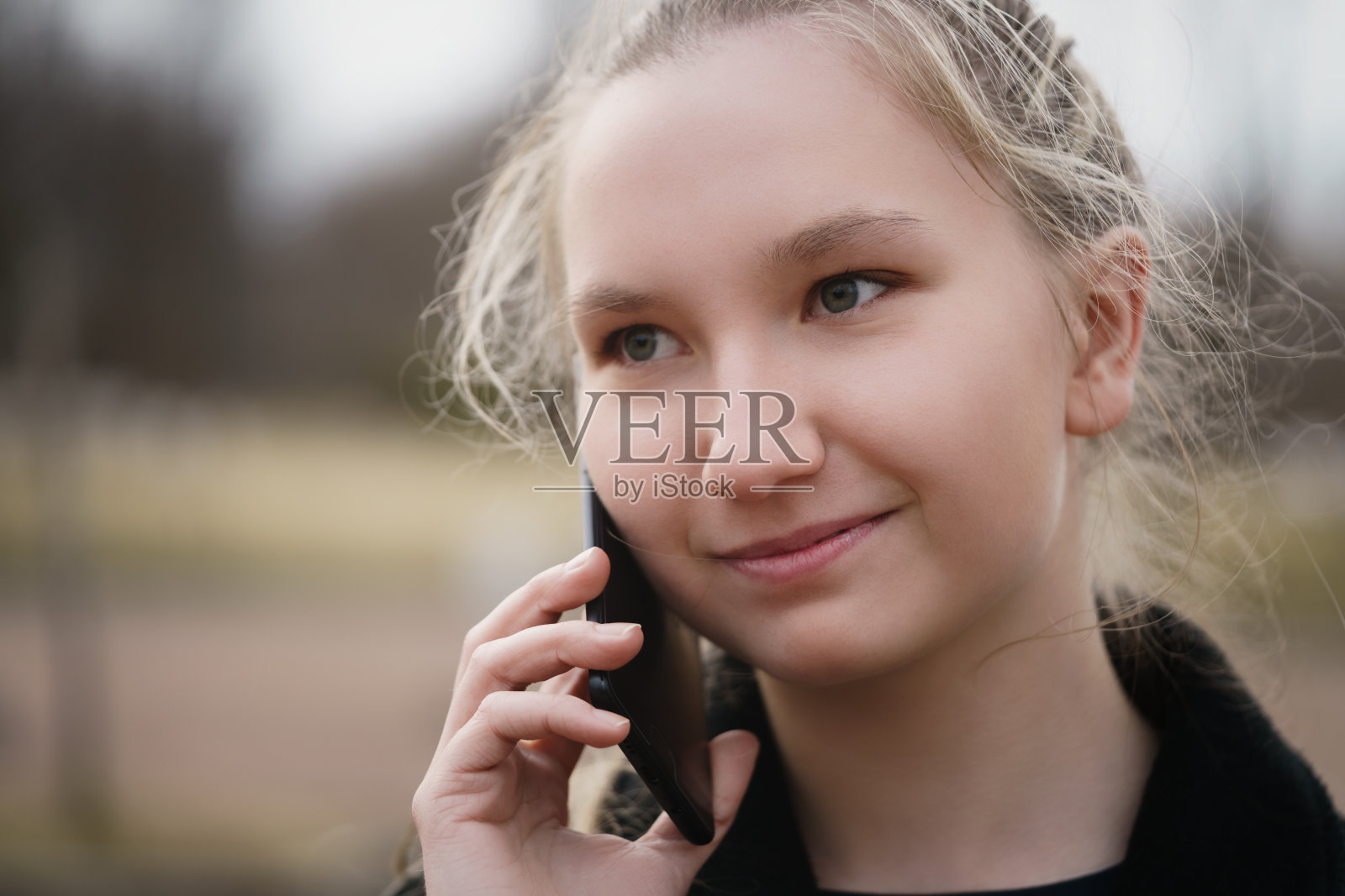 早春时节站在人行道上打电话的少女照片摄影图片