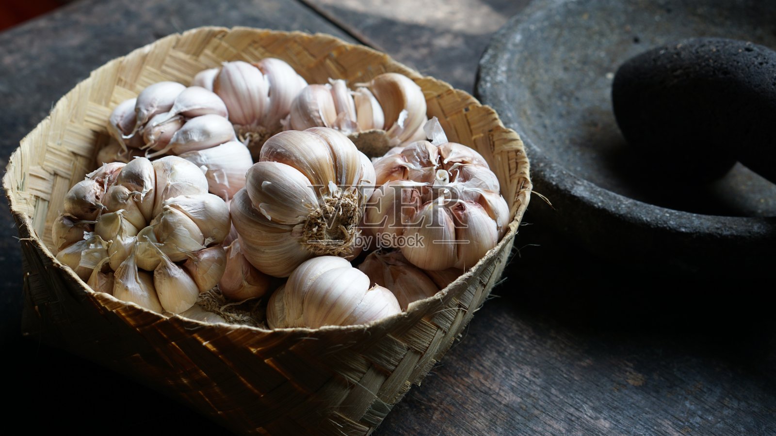 大蒜，新鲜的大蒜，蒜瓣，蒜根放在木筐里。照片摄影图片