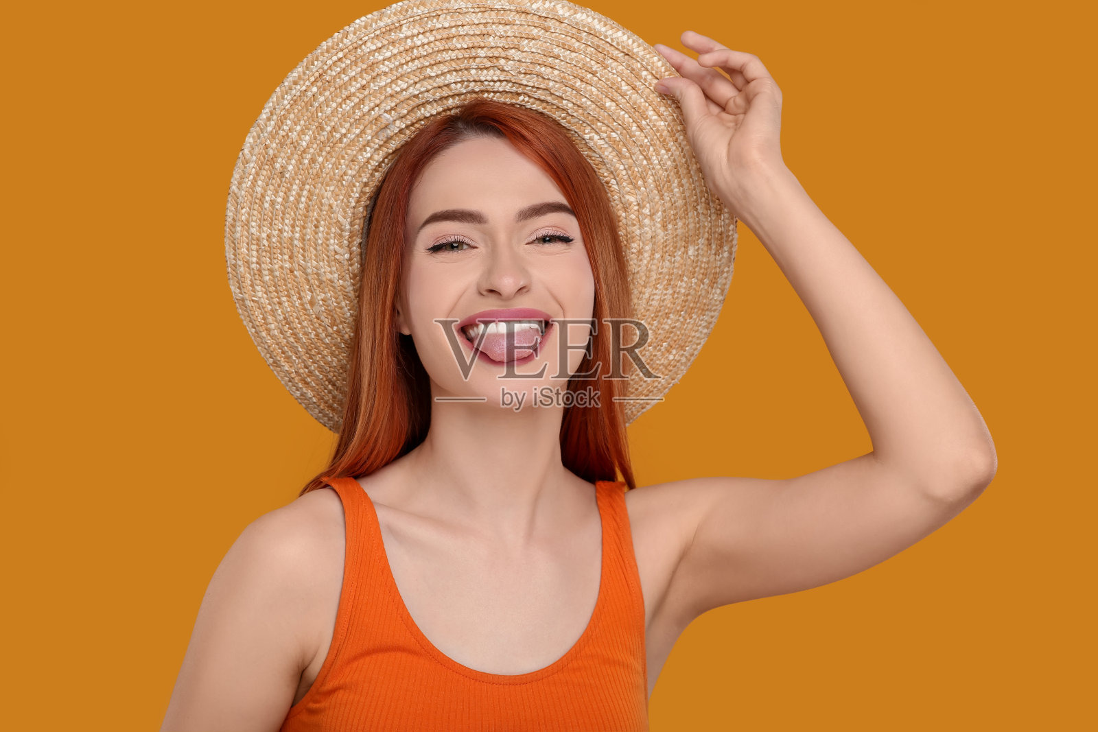 快乐的女人露出她的舌头在橙色的背景照片摄影图片