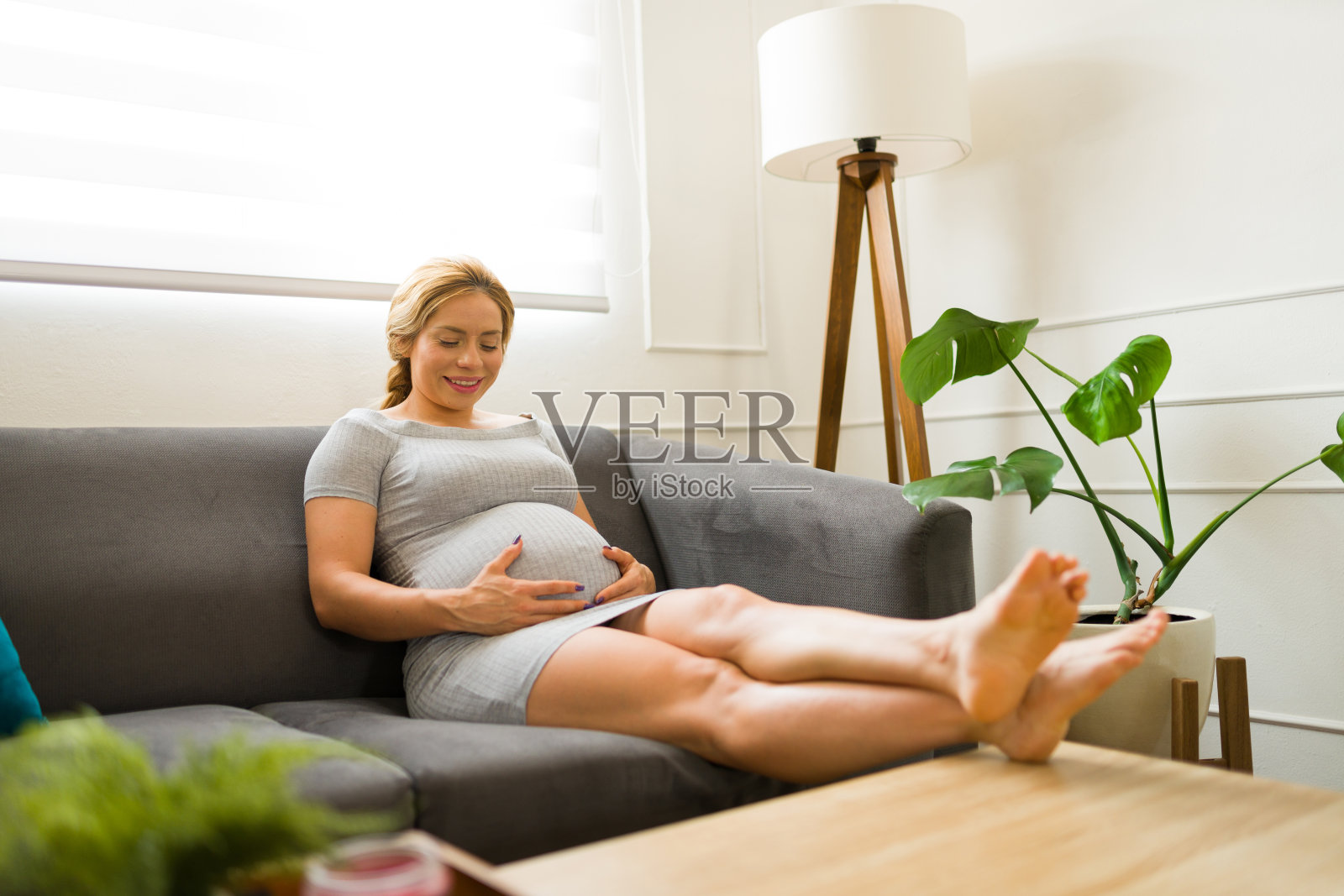 30多岁的漂亮女人对着肚子说话，在家享受怀孕的快乐照片摄影图片