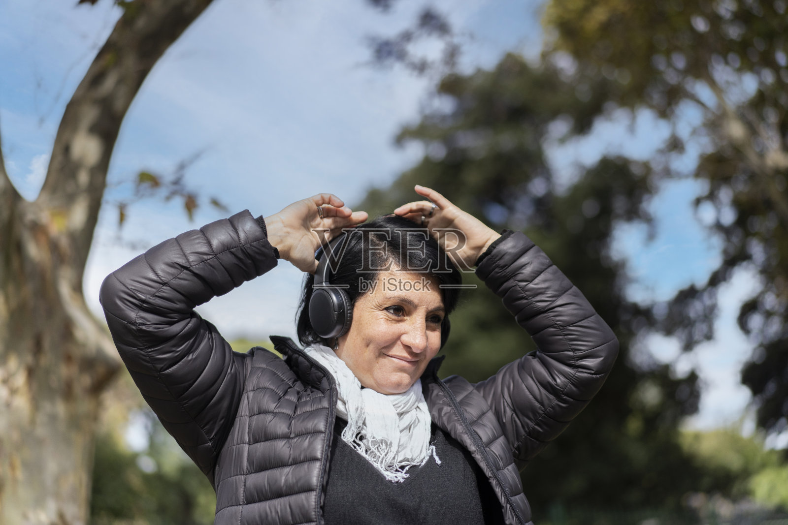 拉丁女人戴着耳机在户外听音乐。照片摄影图片