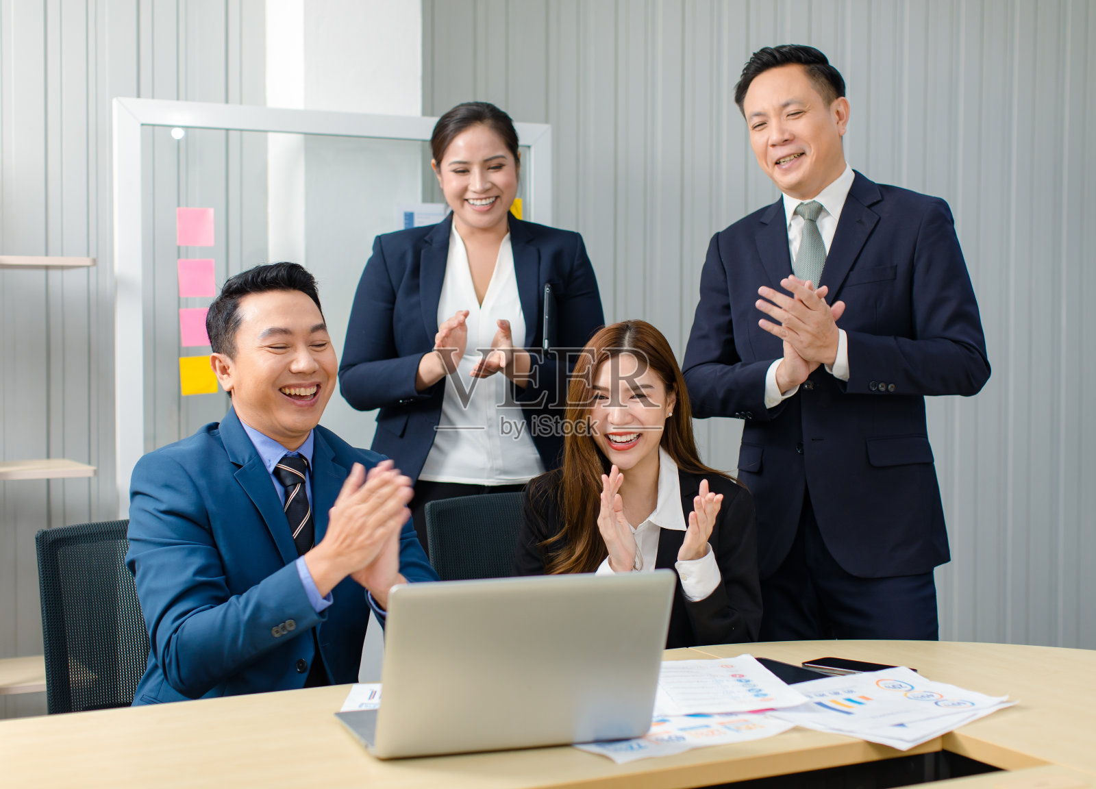 亚洲职业成功的男性女性商人，商务女性，穿着正式的商务套装，坐着站着，微笑着，鼓掌，手鼓掌，在视频电话会议上，在笔记本电脑上照片摄影图片
