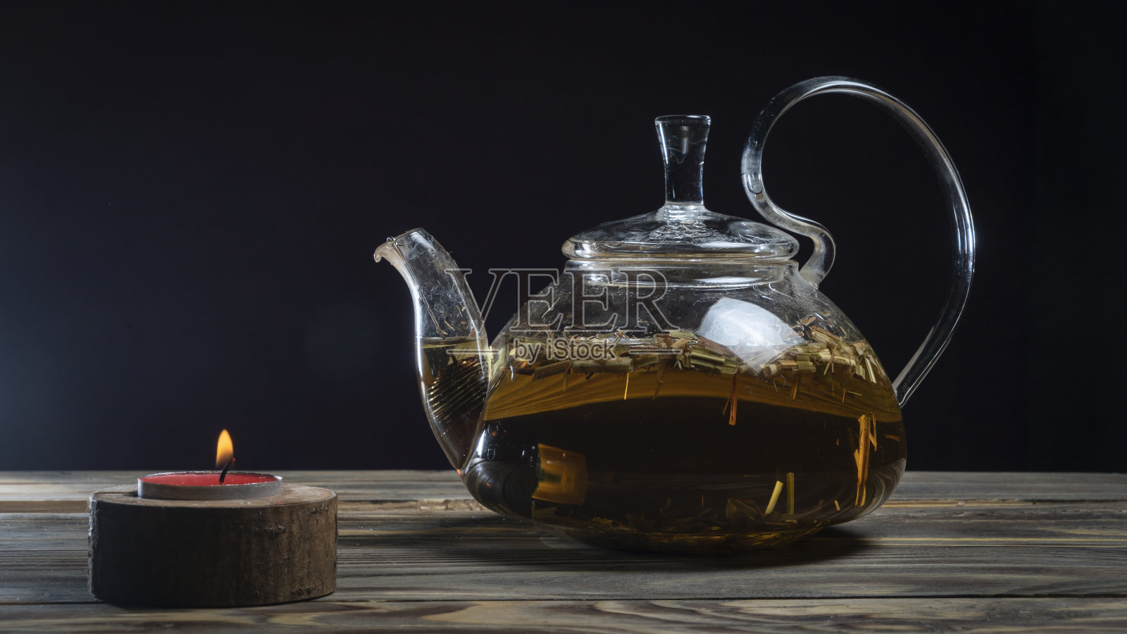 热凉茶在玻璃茶壶在木制桌子上的黑色背景。传统的草本饮料。放置文字或设计。照片摄影图片