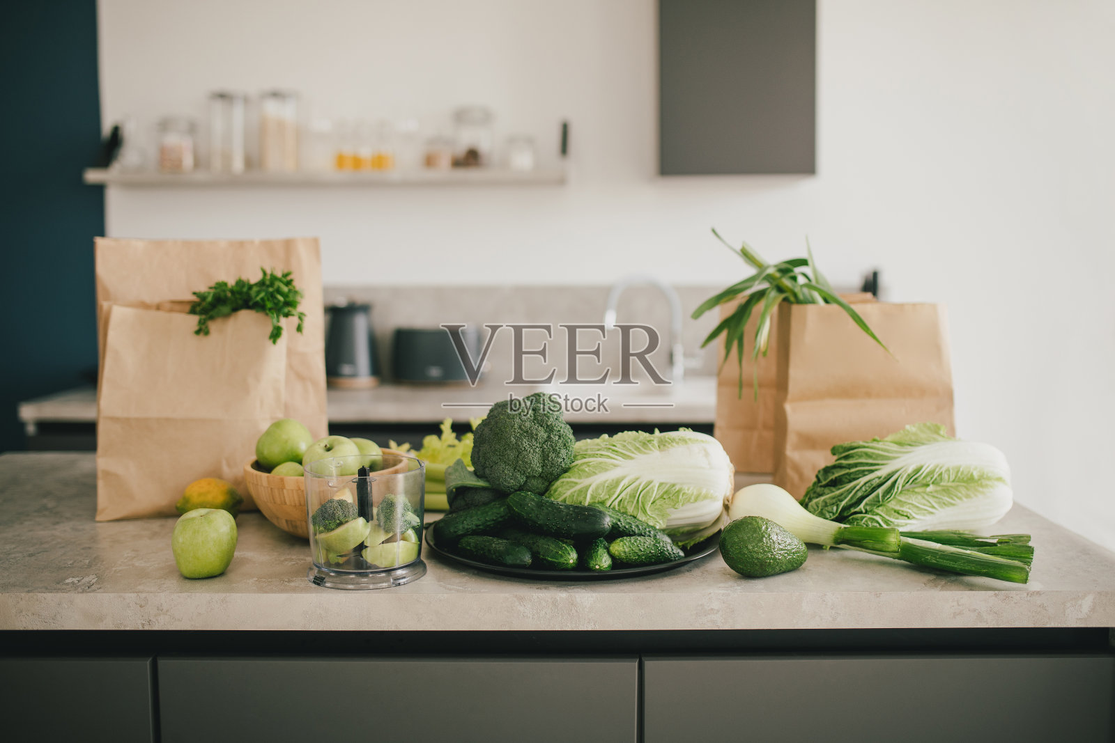 静物与绿色水果和蔬菜在灰色的桌子在厨房内部。照片摄影图片