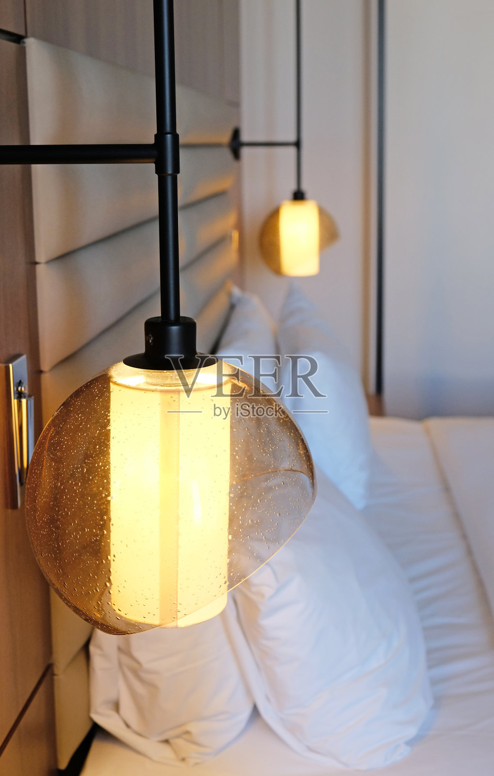 近景卧室阅读灯，黄色光，现代室内设计的家庭或酒店。两个白色柔软的枕头和毯子，时尚舒适的家具。照片摄影图片