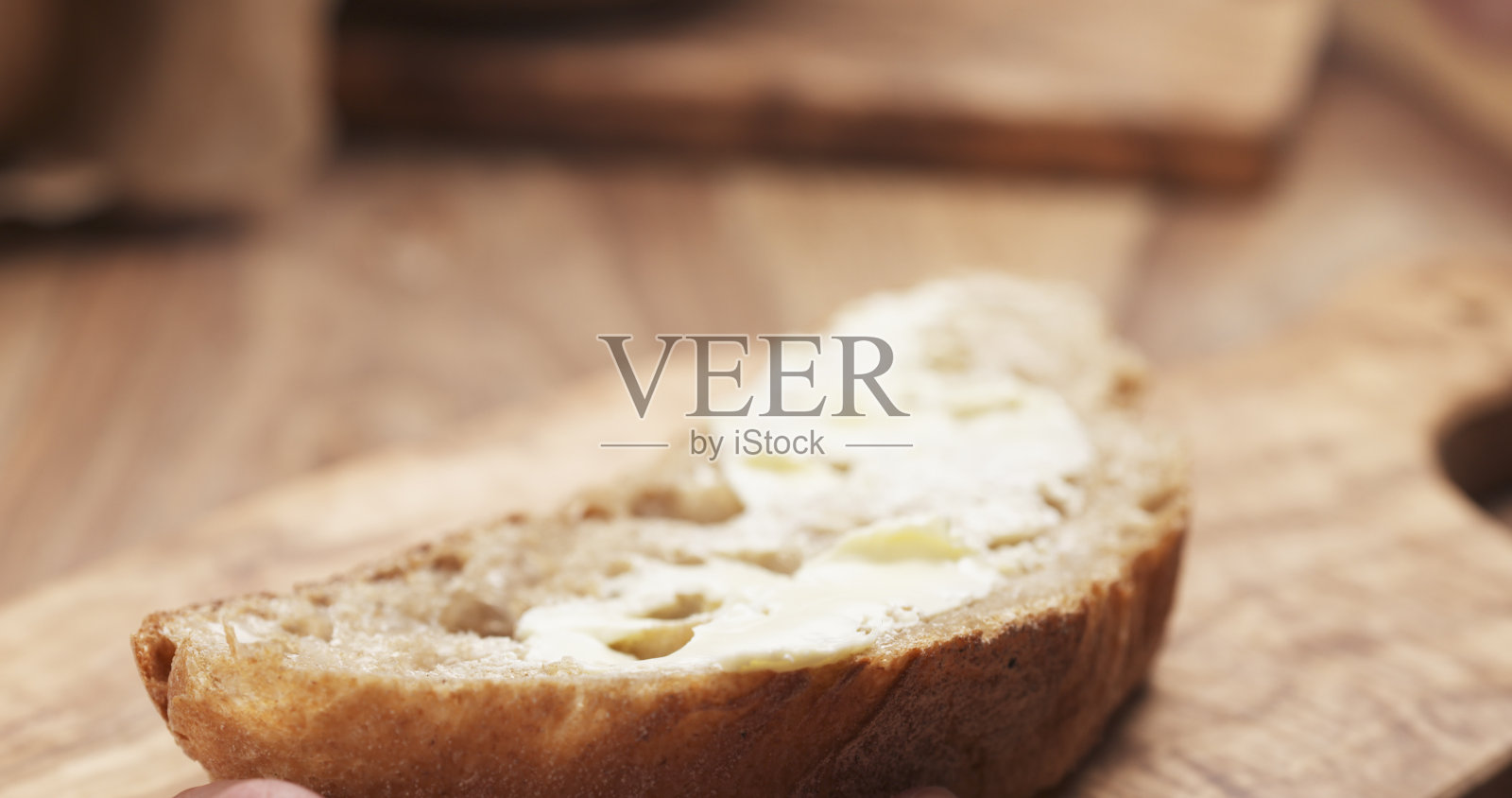 少女用手将黄油涂在一片质朴的面包上照片摄影图片