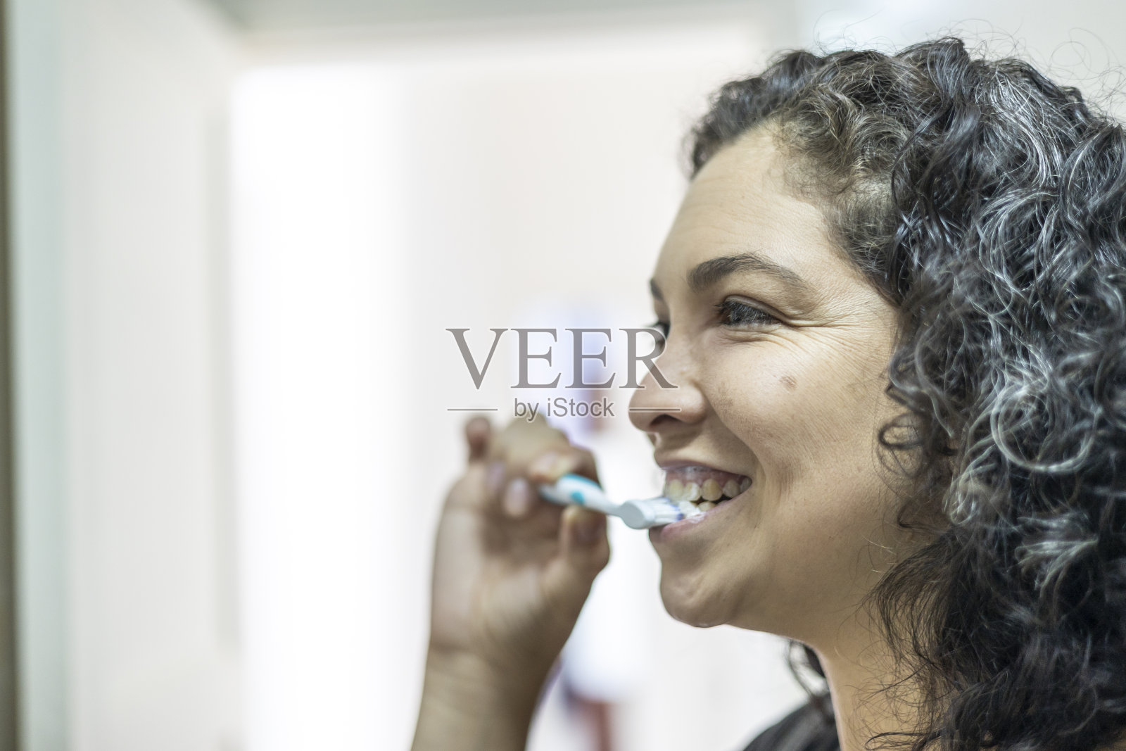 拉丁女人在浴室里愉快地刷牙照片摄影图片