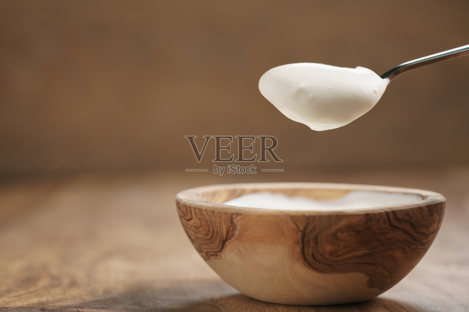 用木碗里的勺子吃有机酸奶照片摄影图片