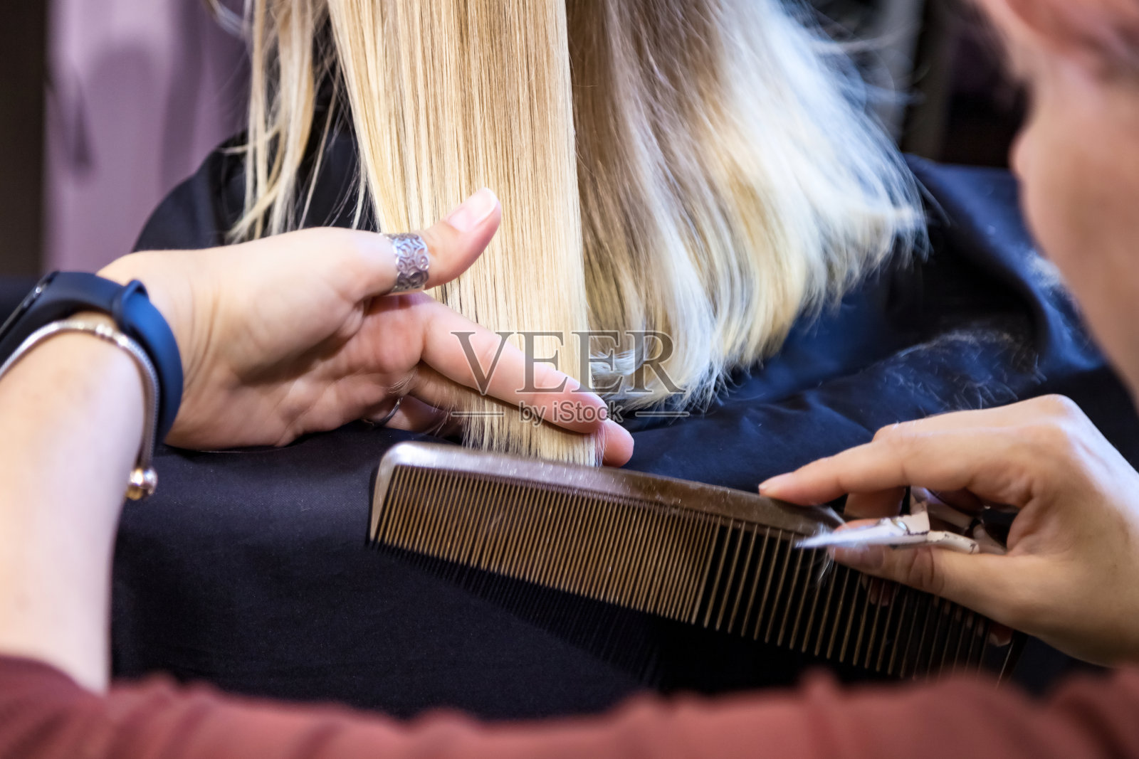 美发沙龙，近距离的理发师为孩子做时尚的发型在理发店。理发师在理发店为可爱的金发小女孩做漂亮的发型。护发，美容理念。复制广告文本空间照片摄影图片