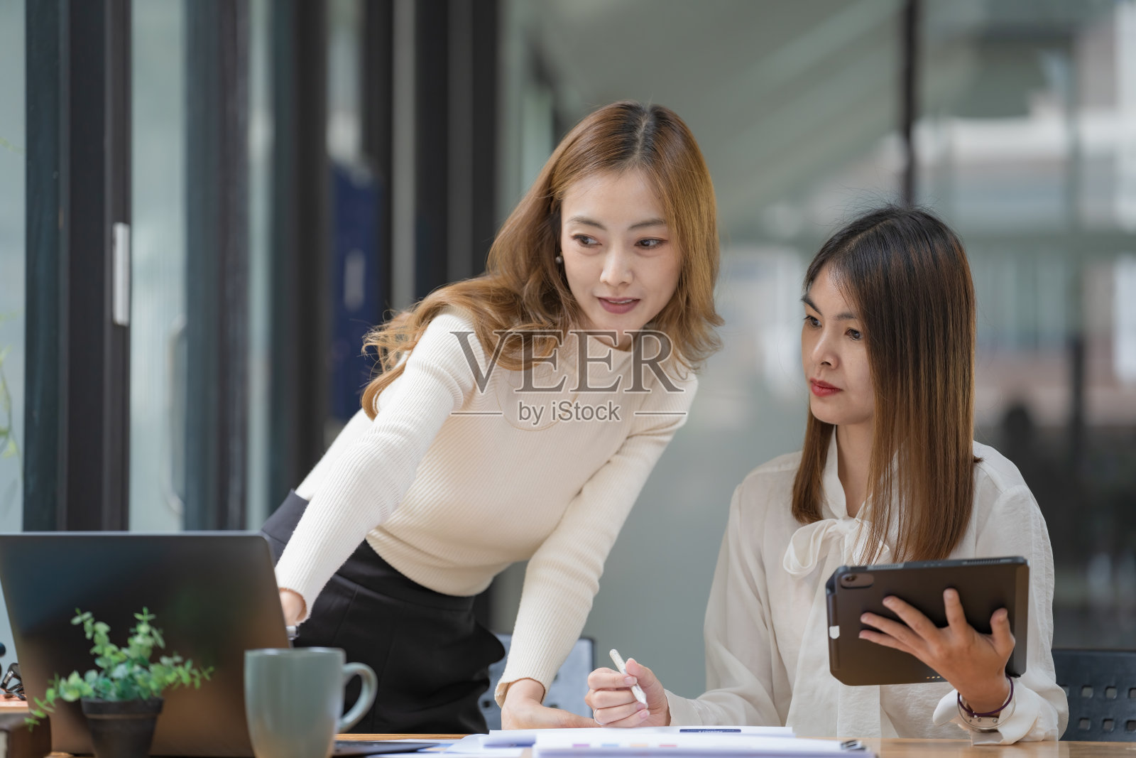 两位年轻的亚洲女企业家在办公室里交谈，咨询，讨论与新创业项目的想法展示，并分析计划营销和投资。照片摄影图片