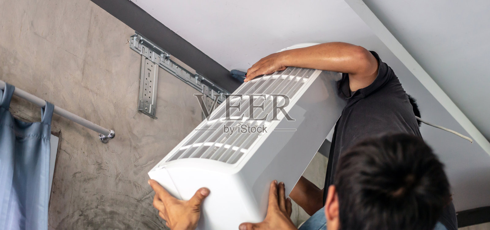 两名技术人员互相帮助将新空调搬到房间安装。照片摄影图片