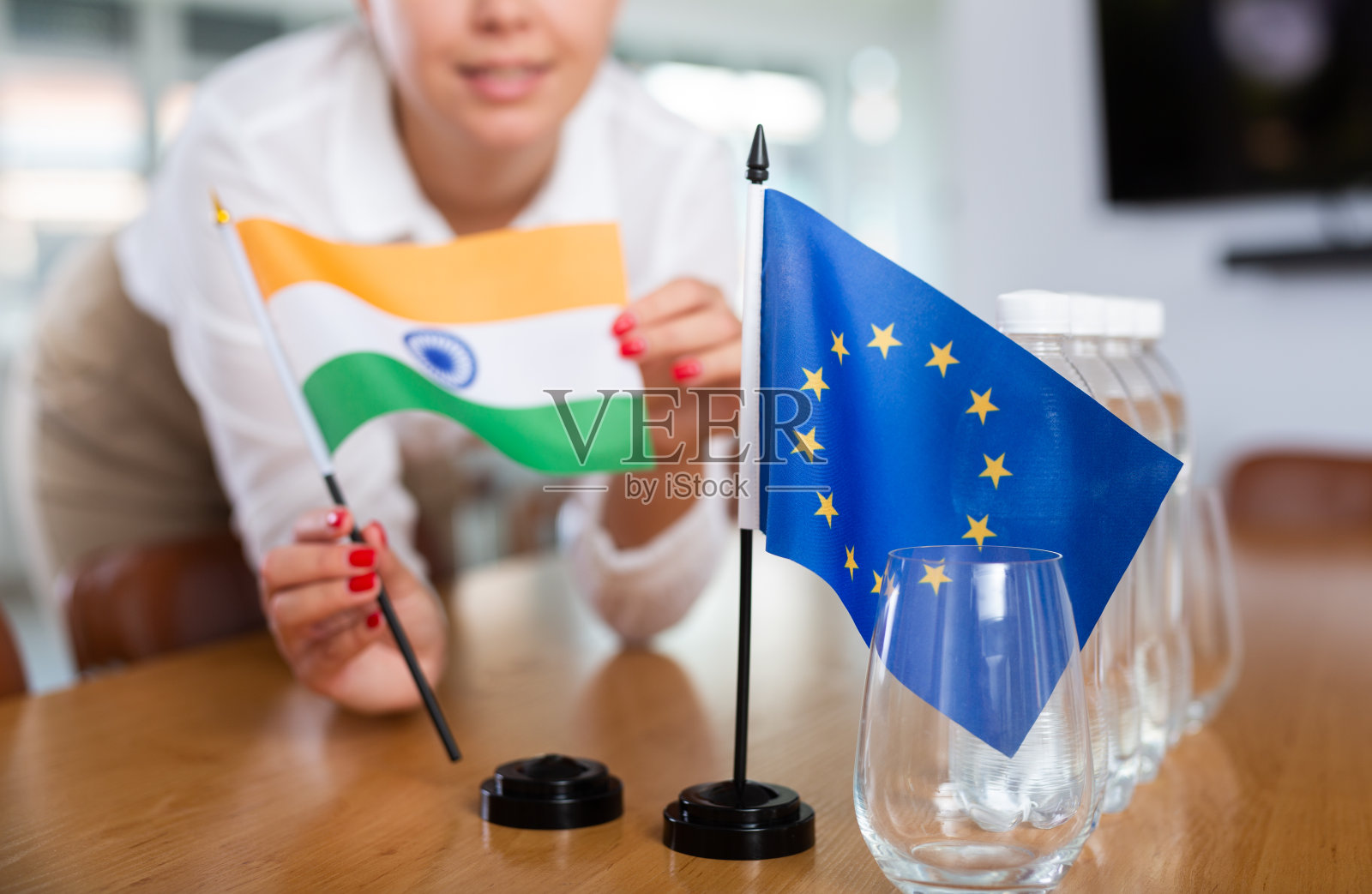 年轻女子把印度和欧盟国旗放在办公室的桌子上照片摄影图片
