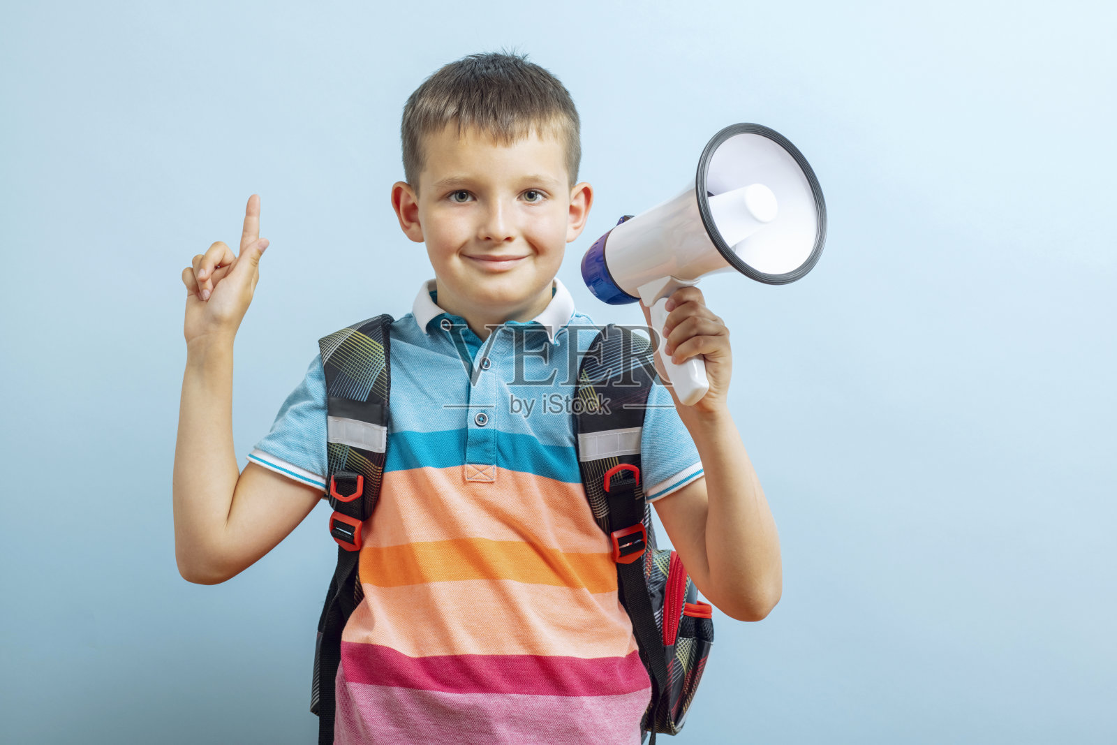 一个小男生用蓝色背景的扩音器大声喊叫照片摄影图片