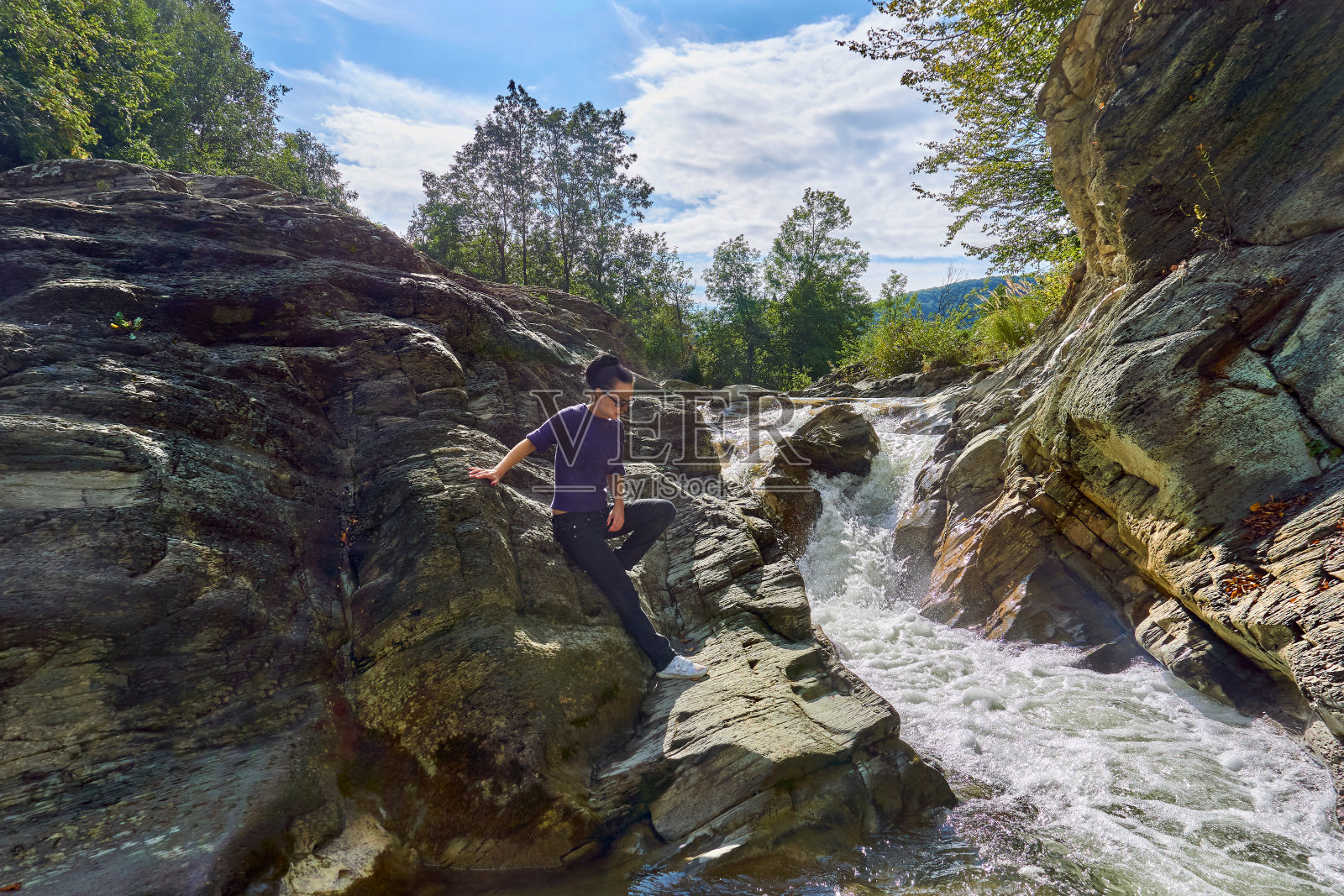 一名年轻女子在山间暴风雨的河边旅游。岩层和石头照片摄影图片
