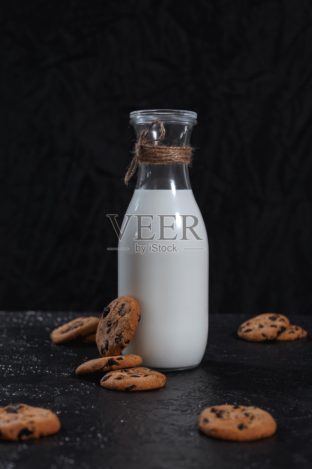 一瓶牛奶和黑色背景的巧克力饼干照片摄影图片