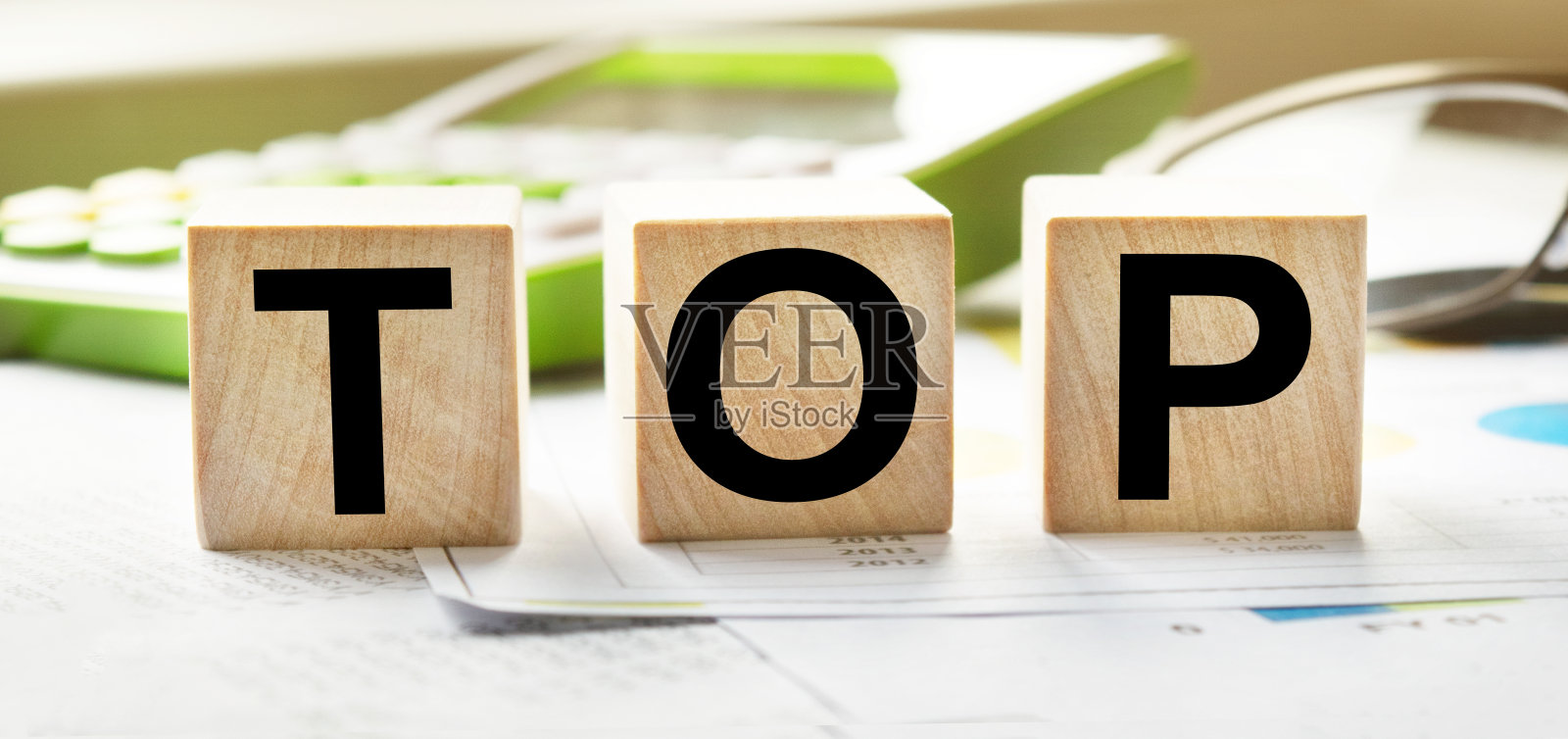 顶部铭文上有木质立方体的纹理。以木块为背景的计算器和商业文件。题词:以金融、商业或经济为主题的题词照片摄影图片