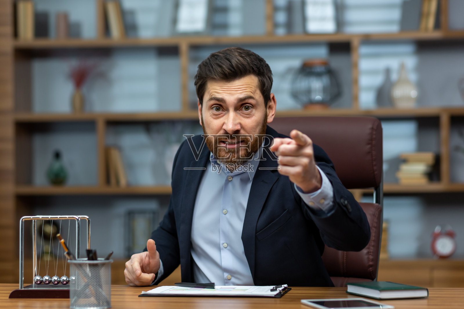 一个愤怒的年轻商人在办公室里与客户、团队、合作伙伴进行视频通话。对工作不满意，紧迫的截止日期，被解雇照片摄影图片