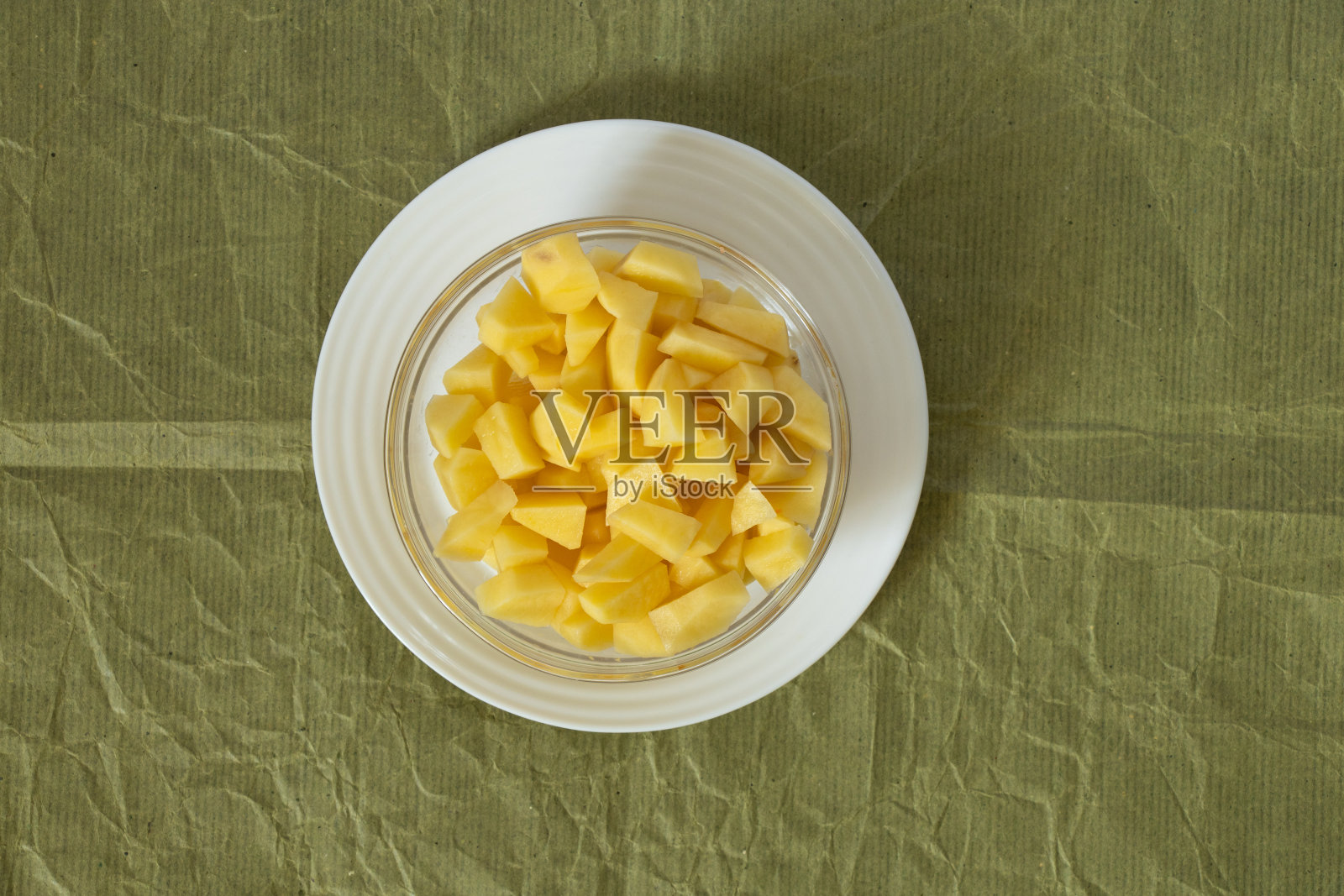 切好的生土豆放在厨房桌子上的盘子里照片摄影图片