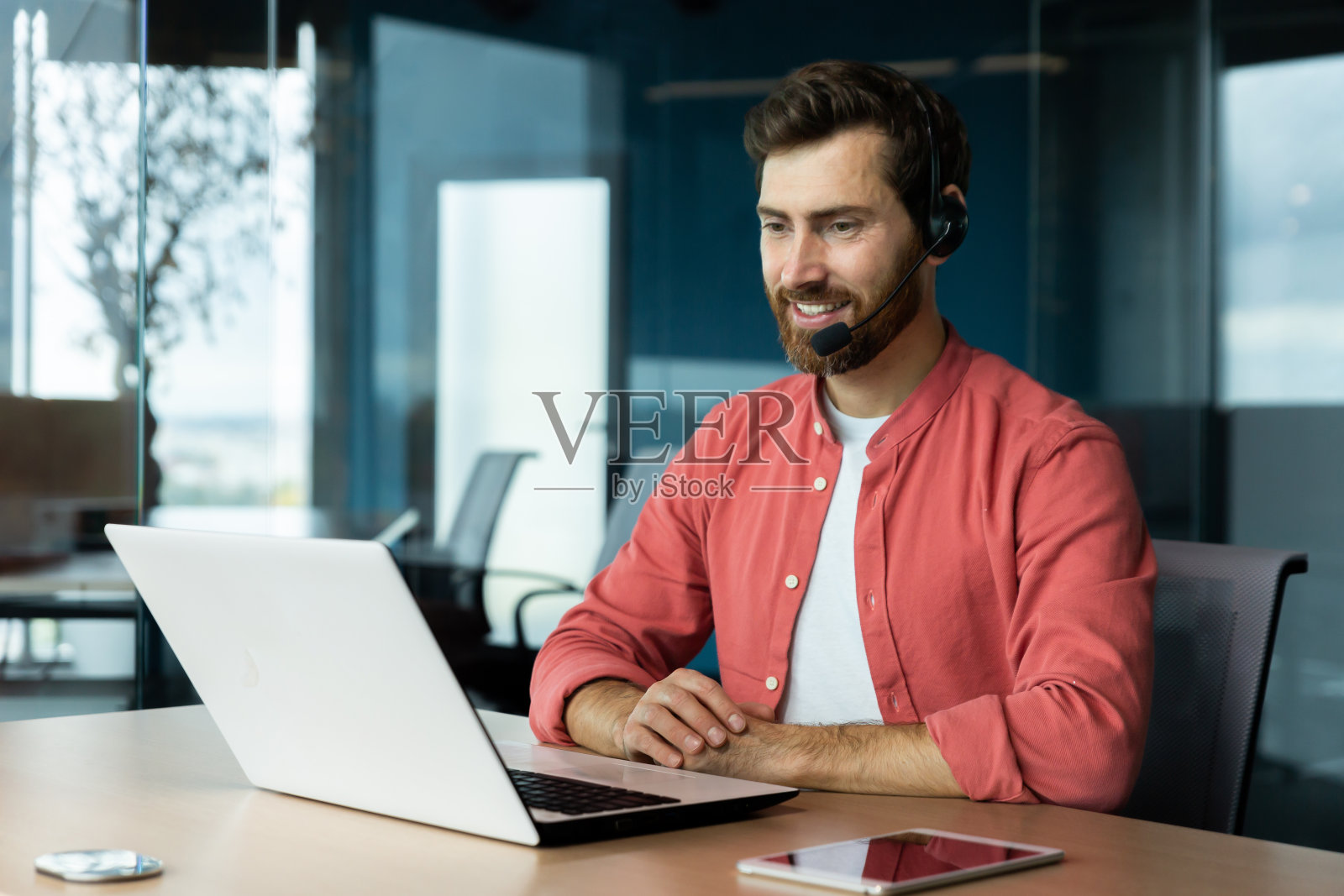 快乐的客服人员带着视频通话耳机和笔记本电脑，微笑着在线咨询客户帮助下订单。照片摄影图片