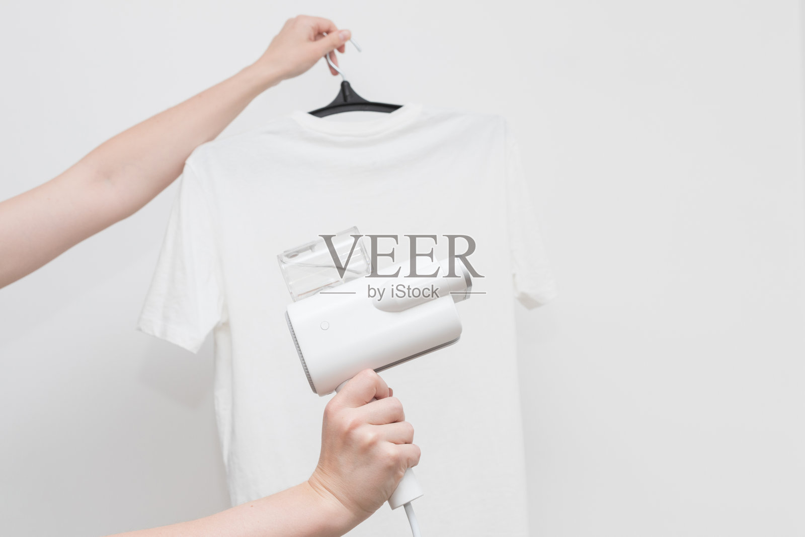 白色t恤背景上的手动蒸笼。特写镜头。衣服在家里照片摄影图片