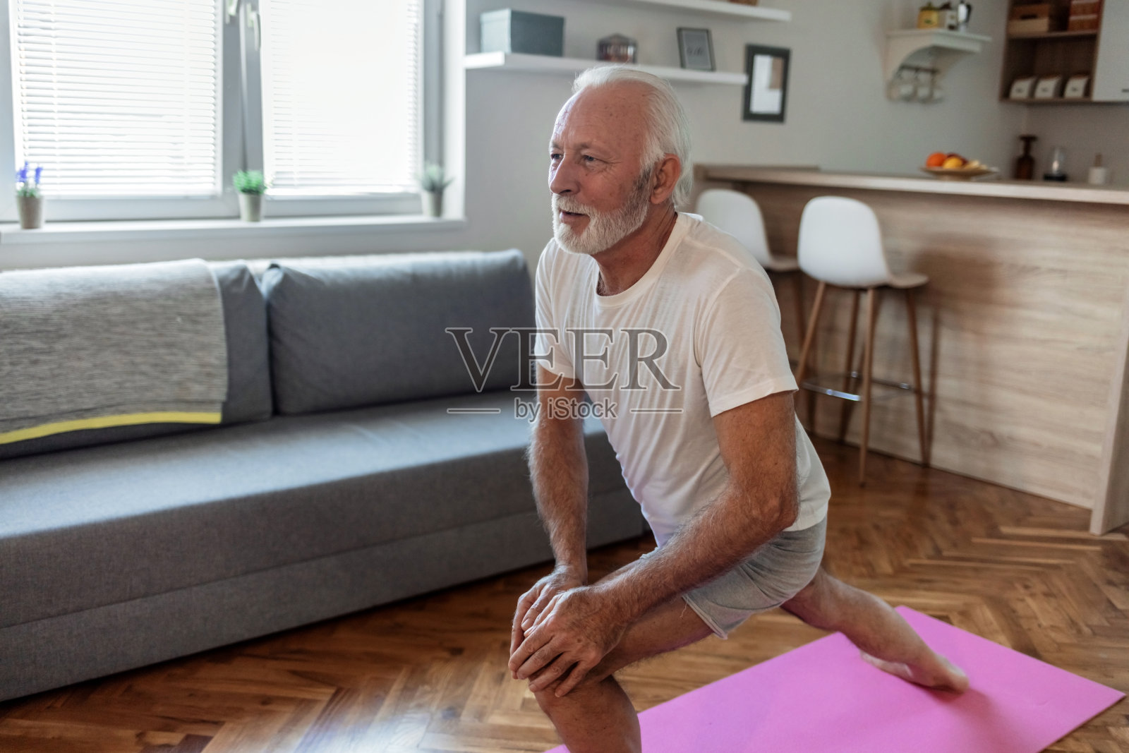 白天，一个放松的成熟男人在家里练习瑜伽。照片摄影图片