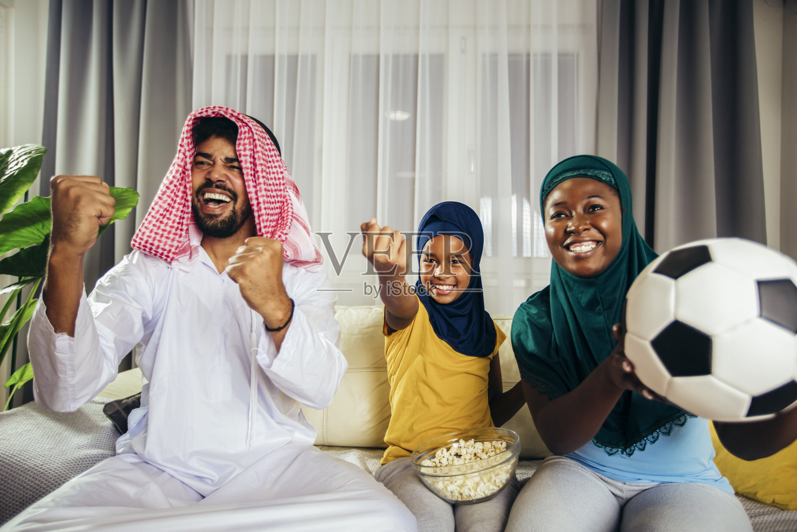 一名阿拉伯男子在观看体育比赛时与家人一起看电视。照片摄影图片