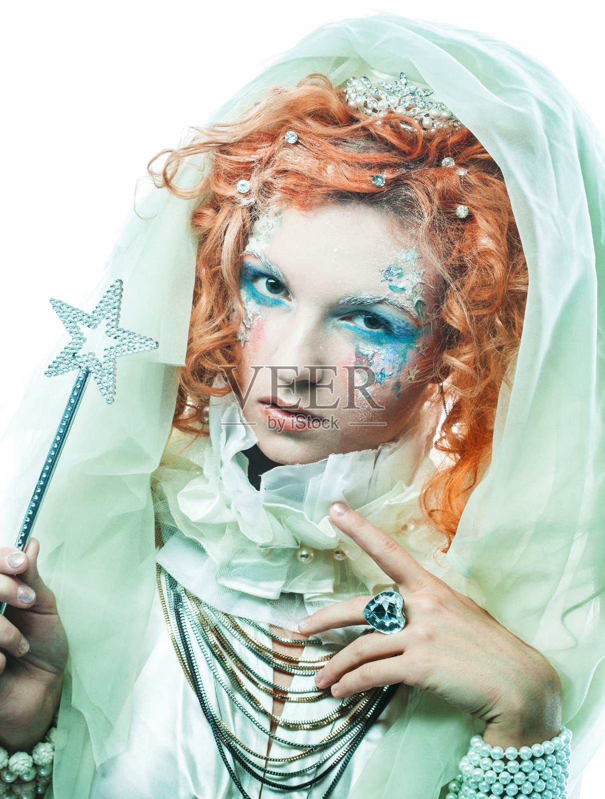 一个迷人的红头发女人穿着新年服装，神话般的仙女手持魔杖。照片摄影图片